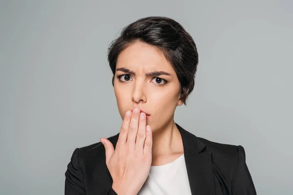 Choqué mixte femme d'affaires couvrant la bouche avec la main isolé sur gris — Photo de stock