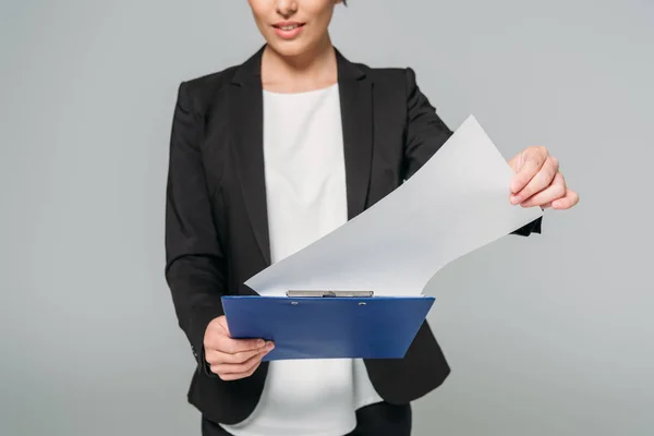 Teilansicht einer gemischt rassischen Geschäftsfrau, die Klemmbrett mit Papier isoliert auf grau hält — Stockfoto