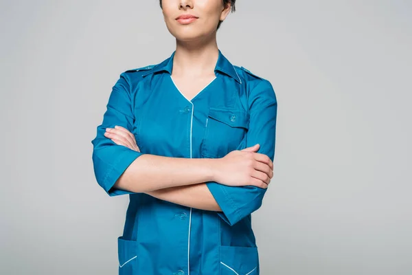 Cropped view of young mixed race nurse posing at camera with crossed arms isolated on grey — Stock Photo