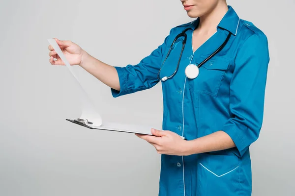 Cropped shot of mixed race doctor looking at clipboard with papers isolated on grey — Stock Photo
