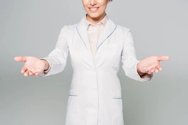 Partial view of mixed race doctor showing welcome gesture isolated on grey — Stock Photo