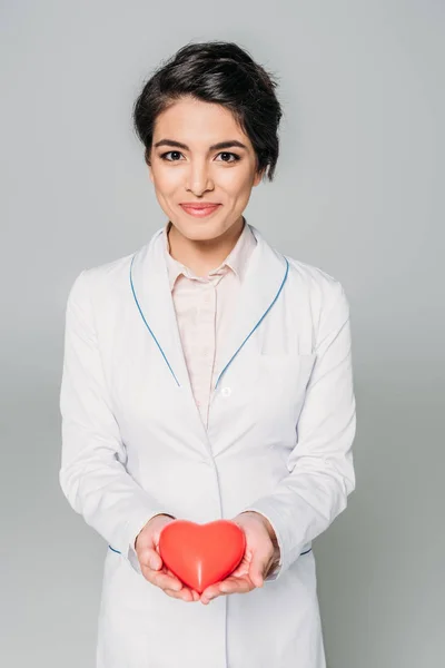 Bello misto gara medico holding cuore modello mentre sorridente a camera isolato su grigio — Foto stock