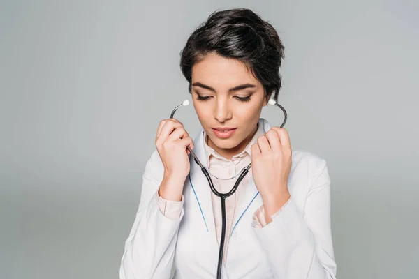 Thoughtful mixed race doctor with stethoscope looking down isolated on grey — Stock Photo