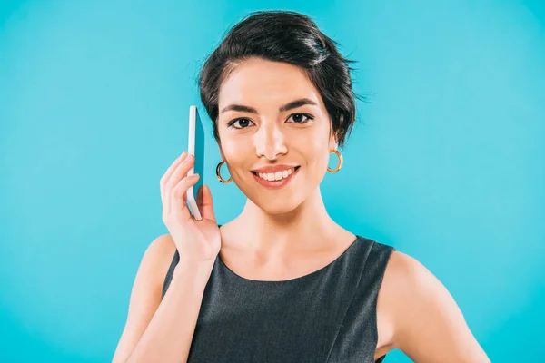 Fröhliche Mischlingshündin, die auf dem Smartphone spricht, während sie eine Kamera auf blauem Grund lächelt — Stockfoto