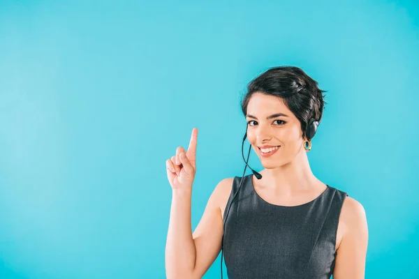 Alegre carrera mixta operador de centro de llamadas en auriculares mostrando idea signo aislado en azul - foto de stock