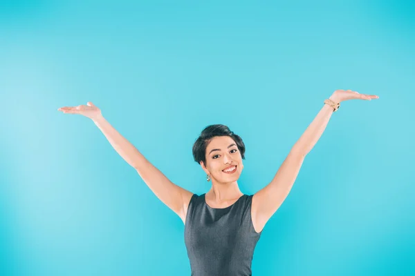 Excitada mujer de raza mixta posando en la cámara con las manos levantadas aisladas en azul - foto de stock