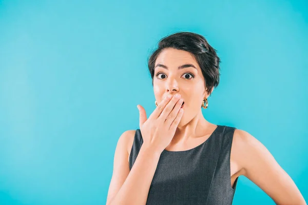 Choqué mixte race femme couvrant la bouche avec la main tout en regardant caméra isolé sur bleu — Photo de stock