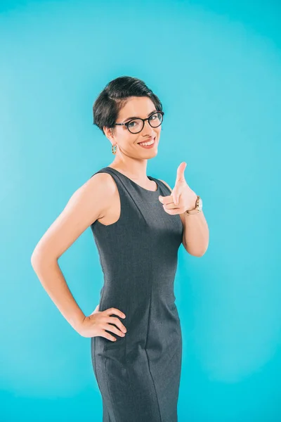 Atractiva mujer de negocios de raza mixta en gafas apuntando con el dedo a la cámara aislada en azul - foto de stock