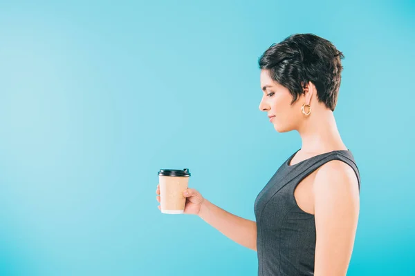 Side view of beautiful mixed race woman holding paper cup on blue background — Stock Photo