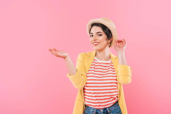 Atractiva chica de raza mixta en sombrero de paja posando en la cámara aislado en rosa - foto de stock