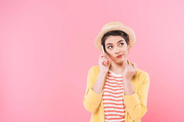 Skeptical mixed race woman in straw hat looking away isolated on pink — Stock Photo