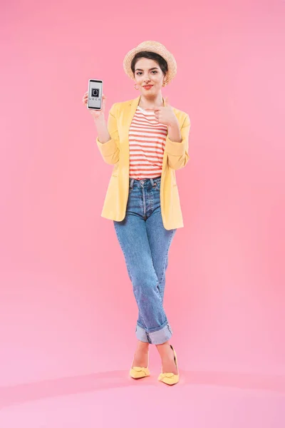 KYIV, UKRAINE - APRIL 24, 2019: Pretty mixed race woman pointing with finger at smartphone with Uber app on screen on pink background. — Stock Photo