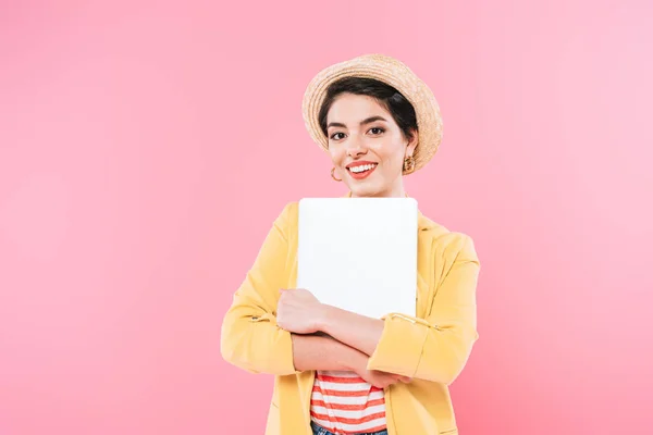 Allegra donna di razza mista che tiene il computer portatile e sorride alla fotocamera isolata sul rosa — Foto stock