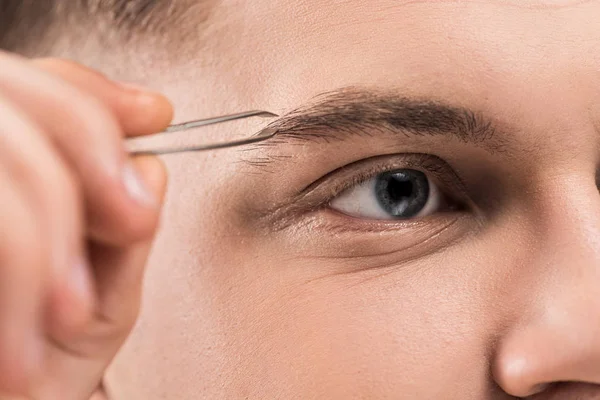 Vue rapprochée du jeune homme à l'aide de pinces à sourcils — Photo de stock