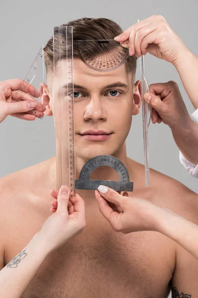 Обрізаний вид пластичних хірургів, що вимірюють обличчя з лінійками та пробками, ізольовані на сірому — стокове фото