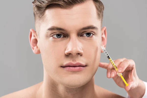 Partial view of cosmetologist holding syringe and young man isolated on grey — Stock Photo