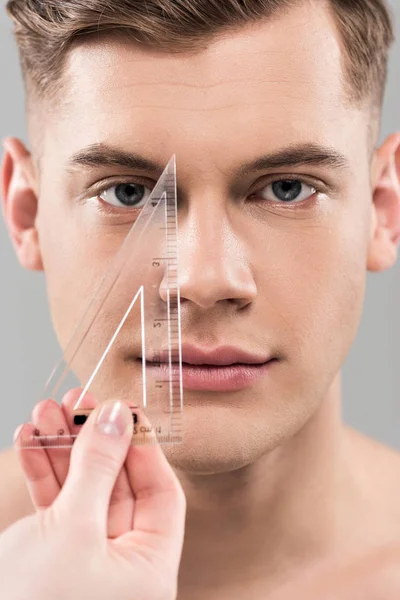 Cropped view of plastic surgeon measuring face with ruler isolated on grey — Stock Photo
