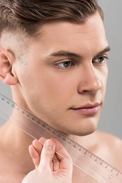 Partial view of plastic surgeon measuring face with ruler isolated on grey — Stock Photo