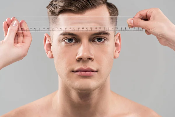 Partial view of plastic surgeons measuring face with ruler isolated on grey — Stock Photo