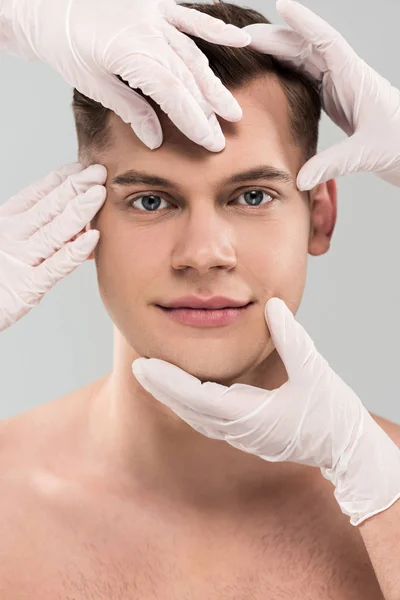 Teilansicht von Kosmetologen in Latexhandschuhen, die Gesicht isoliert auf grau berühren — Stockfoto