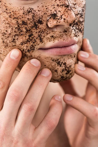 Vista parziale del giovane che applica scrub isolato sul grigio — Foto stock