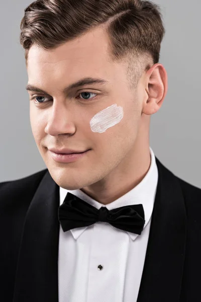 Homme souriant en tenue formelle avec trait crème sur le visage isolé sur gris — Photo de stock