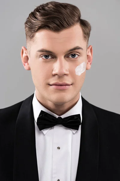 Front view of handsome man in formal wear with cream on face isolated on grey — Stock Photo