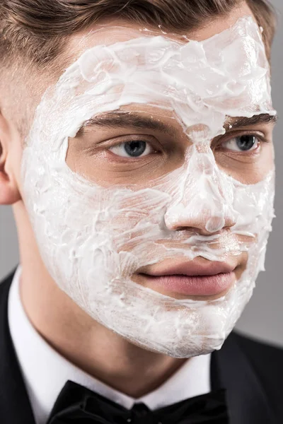 Portrait of man in formal wear with cream on face looking away — Stock Photo