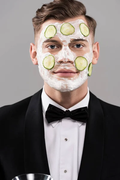 Jeune homme en tenue formelle avec masque facial concombre isolé sur gris — Photo de stock