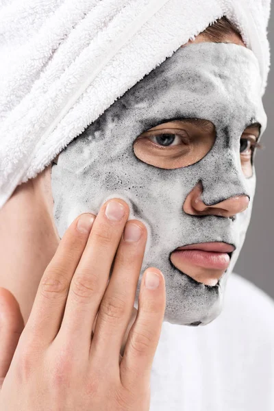 Retrato de hombre con toalla en la cabeza con máscara facial espumosa mirando hacia otro lado - foto de stock