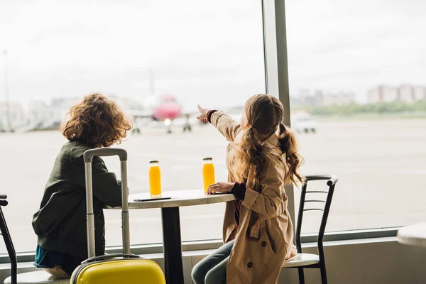 Niño preadolescente apuntando con el dedo al avión y el niño mirándolo - foto de stock