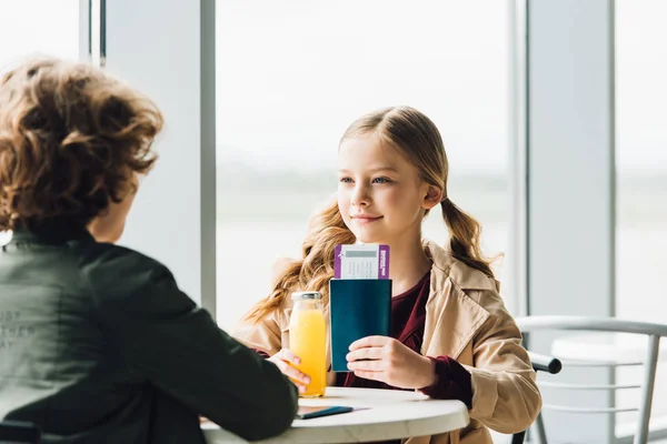 Preteen kid showing passport and air ticket to boy in waiting hall — Stock Photo