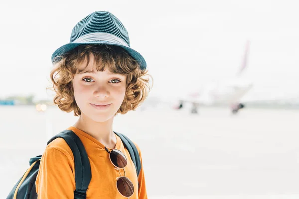 Чарівна дівчинка в капелюсі дивиться на камеру в аеропорту з копіювальним простором — стокове фото