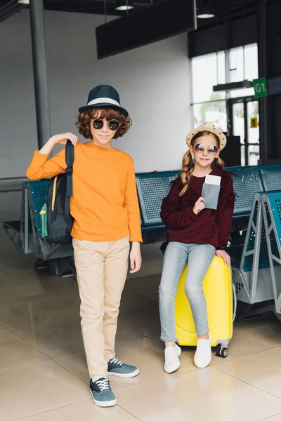 Preteen children in sunglasses with baggage and passport in waiting hall — Stock Photo