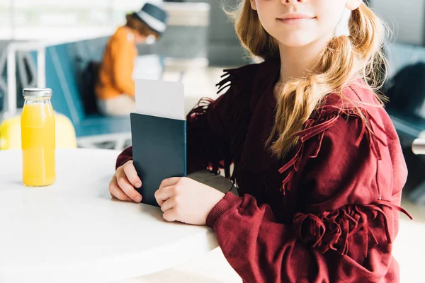 Partial view of preteen kid with passport and air ticket in airport — Stock Photo