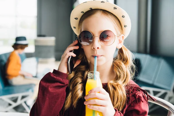 Frühchen trinkt Orangensaft und redet auf Smartphone in Wartehalle — Stockfoto