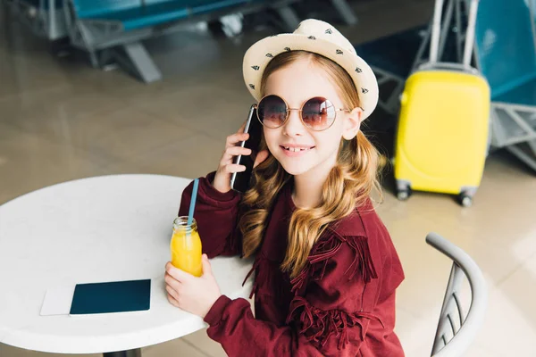 Smiling preteen kid talking on smartphone in waiting hall — Stock Photo