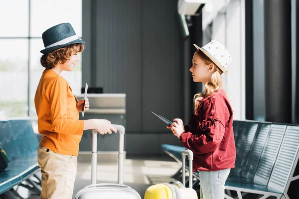 Preteen children with suitcases, air tickets and passports in waiting hall — Stock Photo