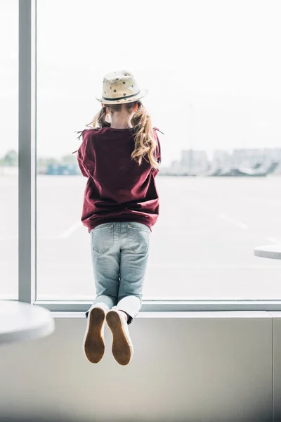 Back view of preteen kid in hat on window during daytime — Stock Photo