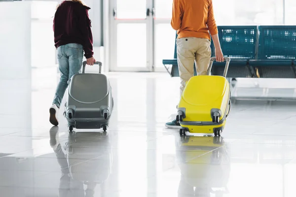 Обрезанный вид на подростков с чемоданами в зале ожидания в аэропорту — стоковое фото