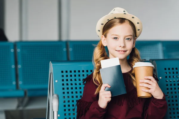 Lächelndes Frühchen mit Pass, Coffee to go und Flugticket im Flughafen — Stockfoto