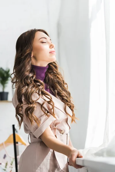 Low angle view of young curly woman standing with closed eyes — Stock Photo
