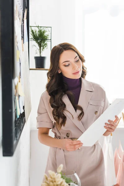 Enfoque selectivo de chica atractiva y rizada sosteniendo papel en blanco en las manos - foto de stock