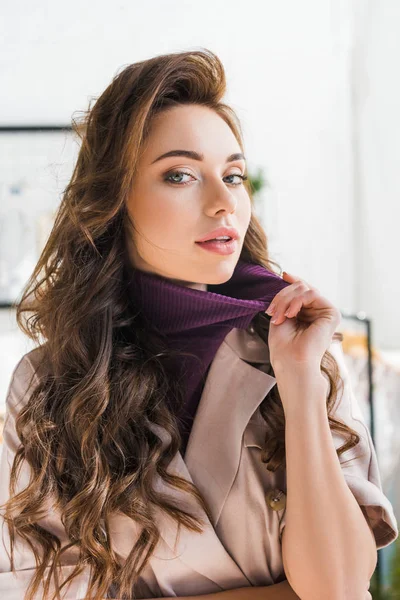 Jolie jeune femme bouclée touchant des vêtements dans le studio de design — Photo de stock