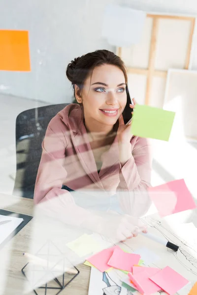 Selektiver Fokus der glücklichen Frau, die im Büro mit dem Smartphone spricht — Stockfoto