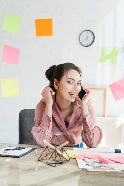 Foco seletivo de mulher alegre falando no smartphone no escritório — Fotografia de Stock