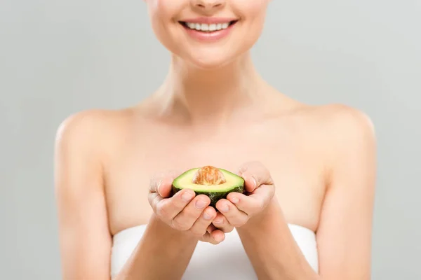 Cropped view of cheerful woman holding half of ripe avocado isolated on grey — Stock Photo