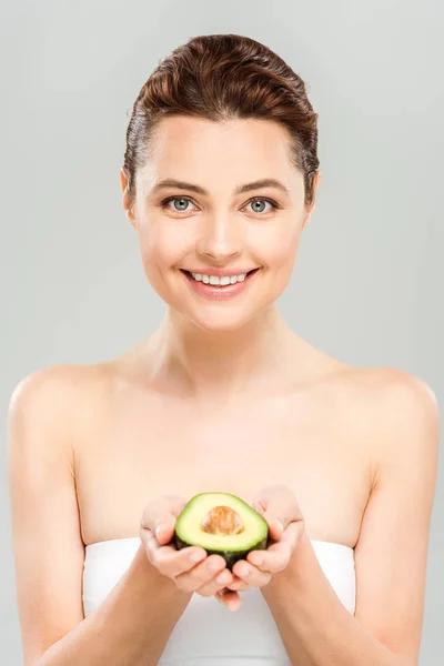 Fröhliche Frau hält Hälfte der reifen Avocado isoliert auf grau — Stockfoto