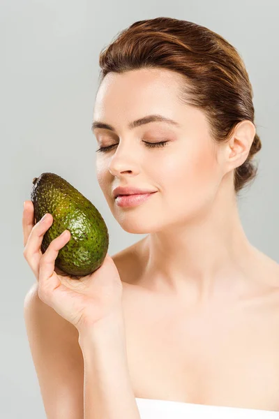 Glückliche Frau mit geschlossenen Augen, die reife Avocado isoliert auf grau hält — Stockfoto
