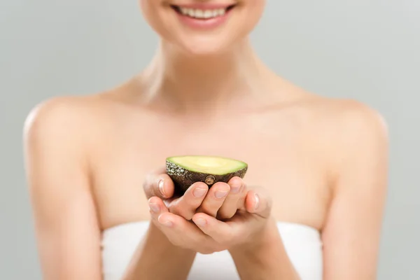 Abgeschnittene Ansicht einer glücklichen Frau, die die Hälfte der Bio-Avocado isoliert auf grau hält — Stockfoto